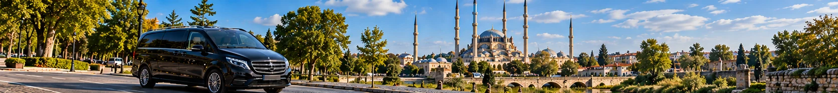 Illustrative black minivan travelling towards Edirne, historic mosque and Thrace countryside